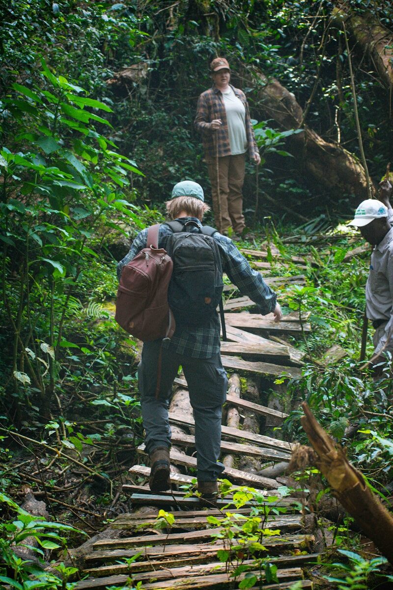 a group of people walking across a wooden bridge