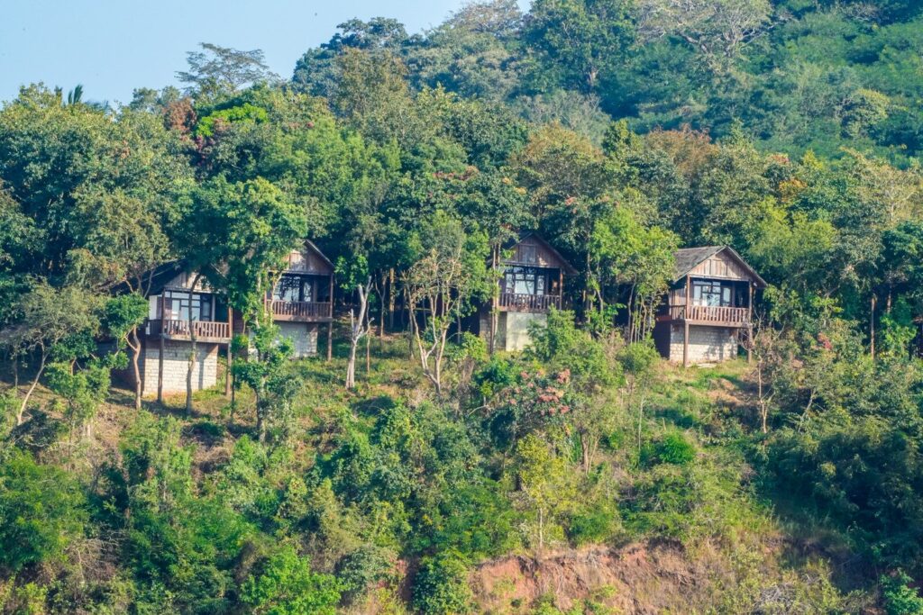 Three wooden cabins nestled on a lush green hillside.